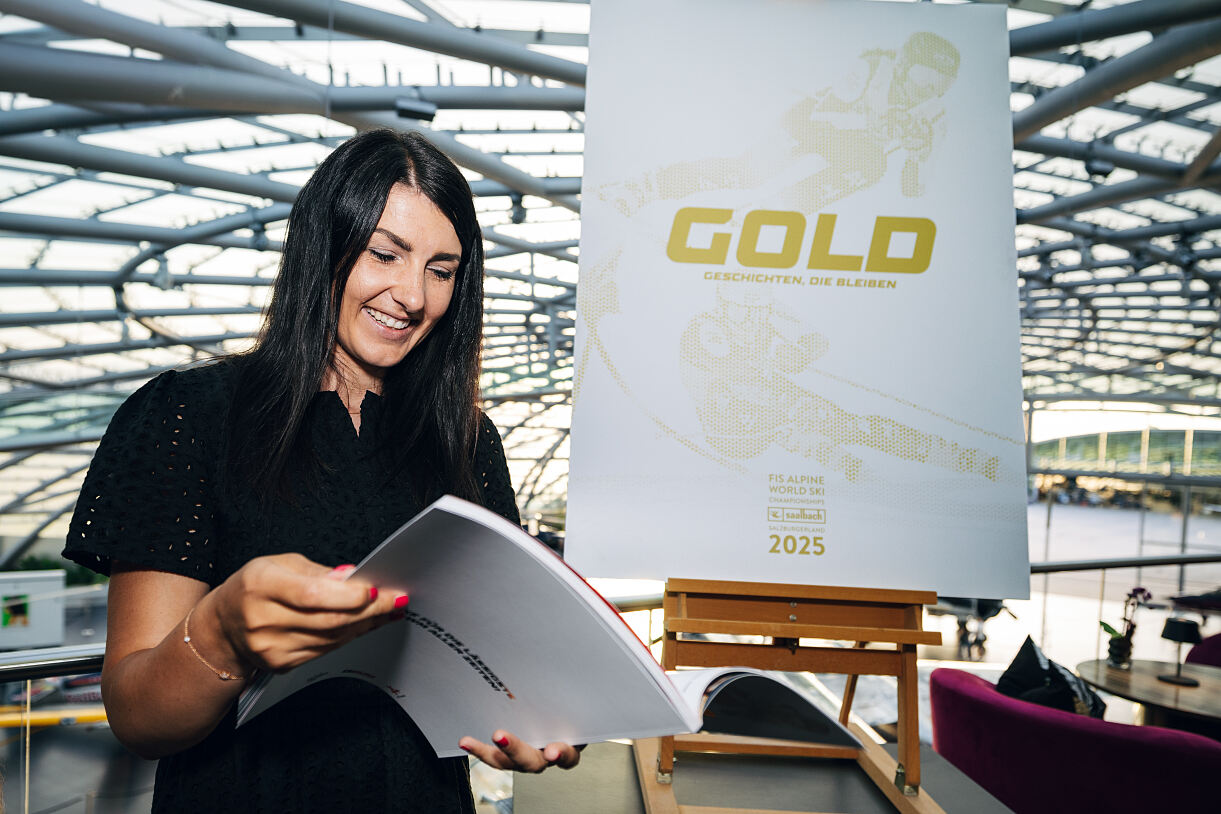 Stephanie Venier schmökert im neuen Magazin, am Cover ist sie neben Raphael Haaser zu sehen