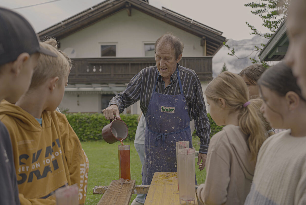 Werner Singer gisst mit Kindern aus Götzens Kerzen