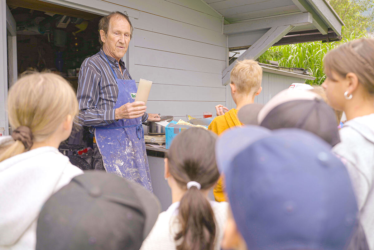 Werner Singer gisst mit Kindern aus Götzens Kerzen